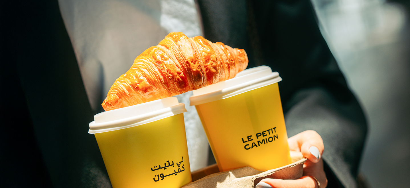 Le Petit Camion specialty coffee cups and croissant at café in Doha Qatar